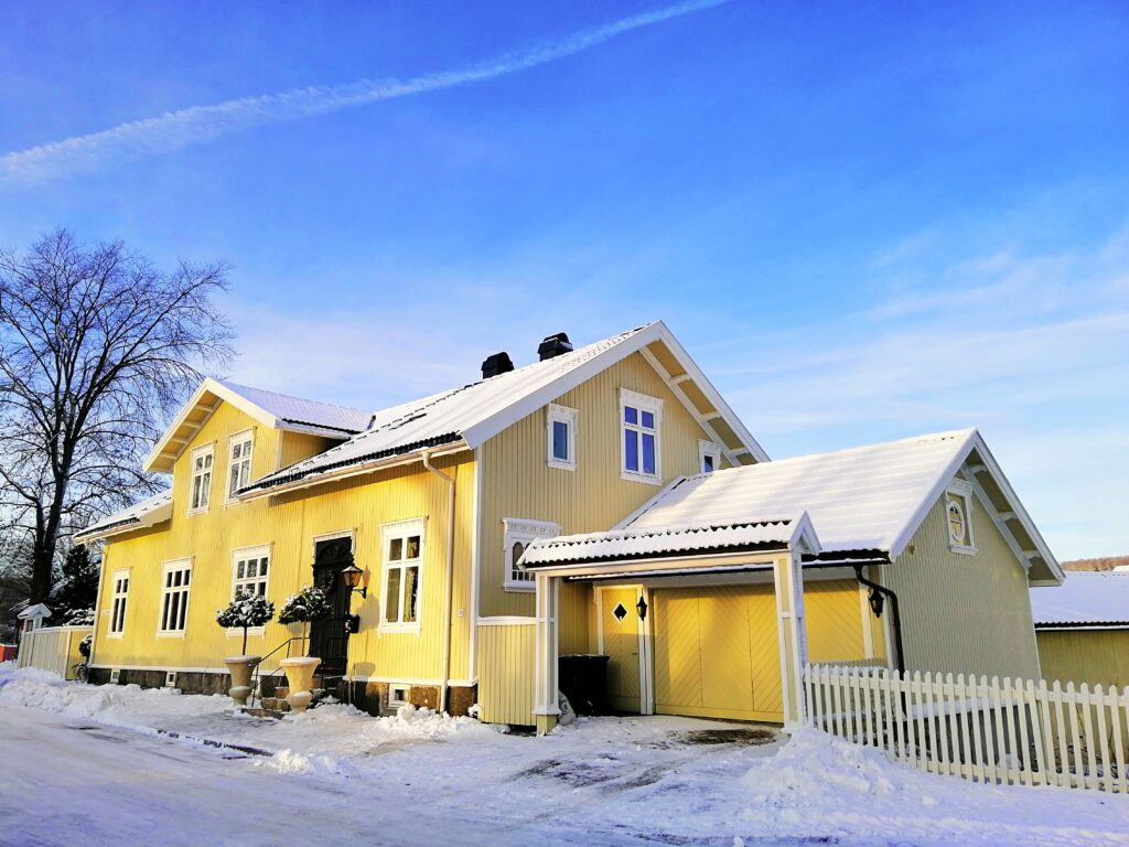 Yellow house surrounded by trees covered in the snow under a cloudy sky in Larvik in Norway Yksityinen Lastenkoti
